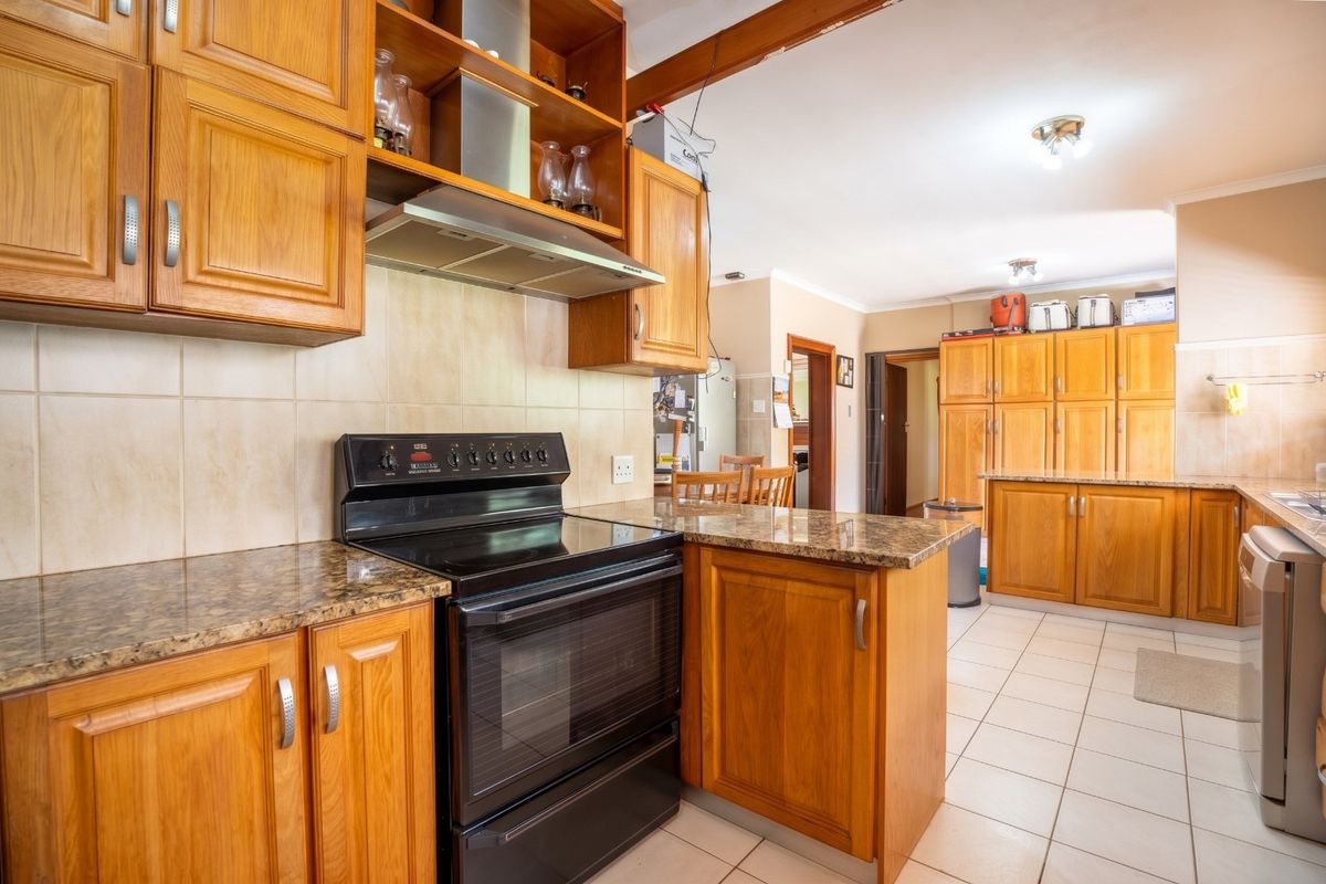 A spacious kitchen featuring warm wooden cabinetry, granite countertops, a tiled backsplash, and a freestanding oven, offering ample storage and functional workspace.