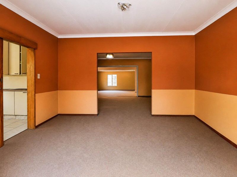 An empty, spacious living area featuring neutral carpeting and a two-tone painted wall finish, providing a blank canvas for interior design updates.
