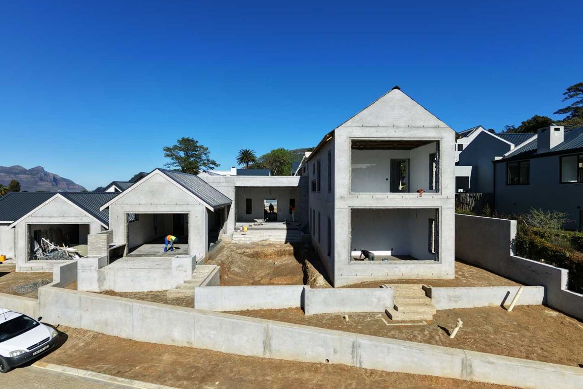 Aerial view of a residential property under construction, featuring a multi-level concrete structure, retaining walls, and an unfinished exterior landscape.