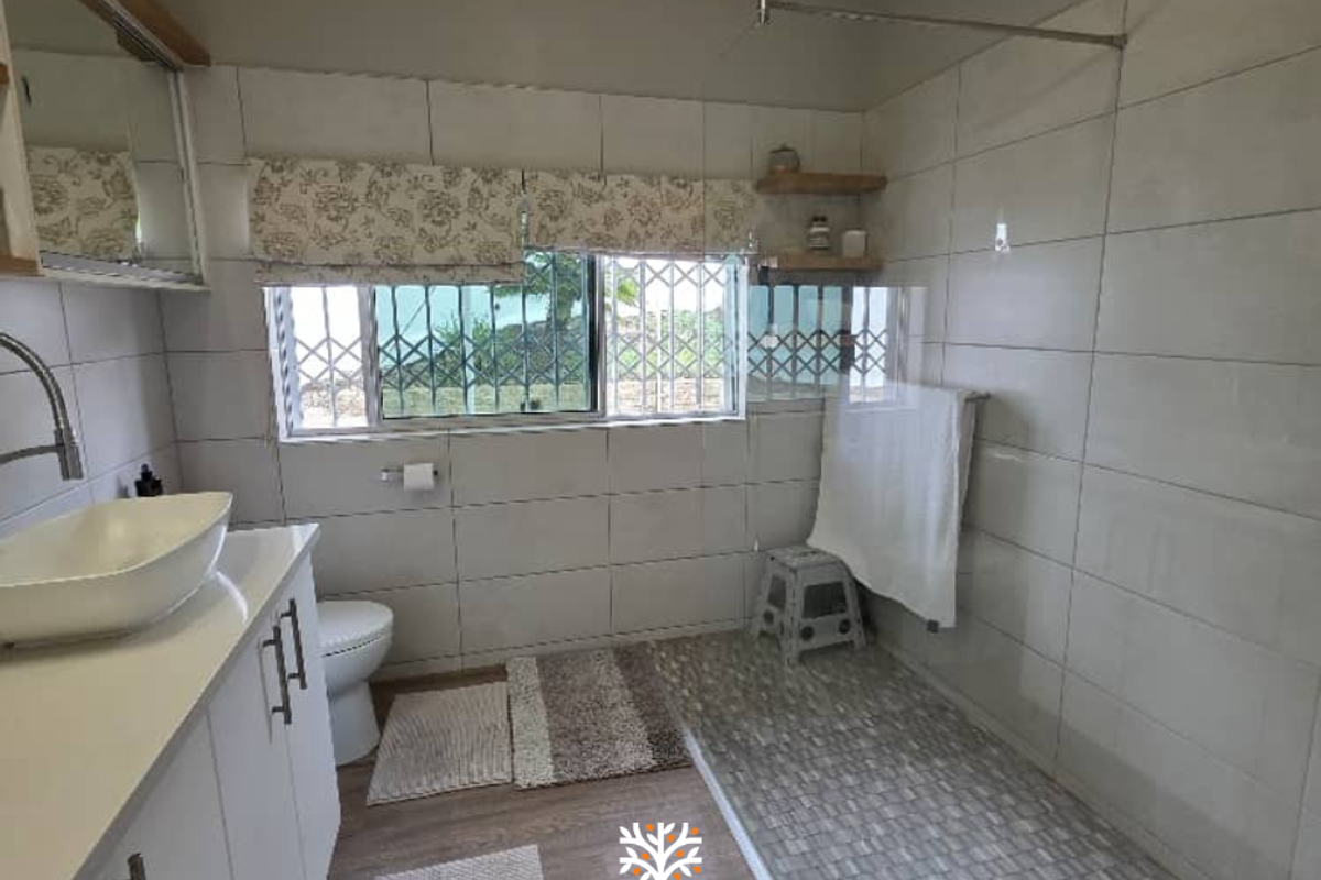 Modern bathroom featuring a walk-in shower with mosaic tile flooring, a vessel sink vanity, and large format wall tiles.