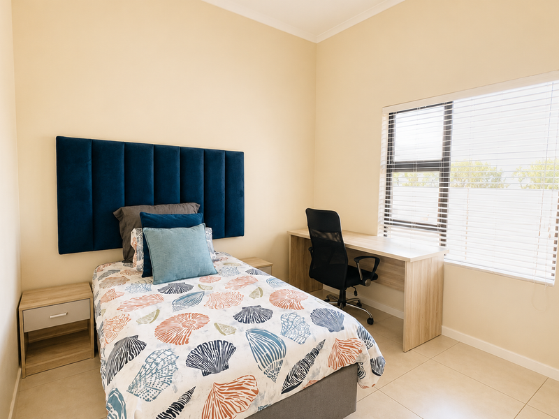 A well-maintained bedroom featuring tiled flooring, a built-in desk, and venetian blinds, offering a clean and functional living space.