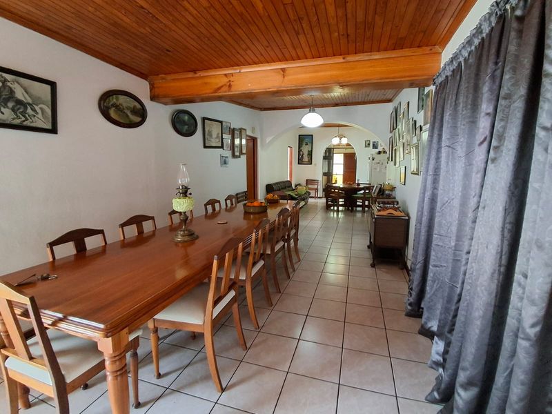 Spacious open-plan dining and living area featuring a warm timber ceiling with exposed beams and neutral ceramic floor tiles.
