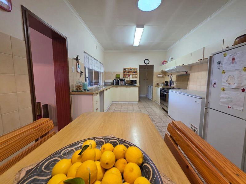 A functional kitchen featuring tiled flooring, built-in cabinetry, a tiled backsplash, and a freestanding oven with an extractor fan.
