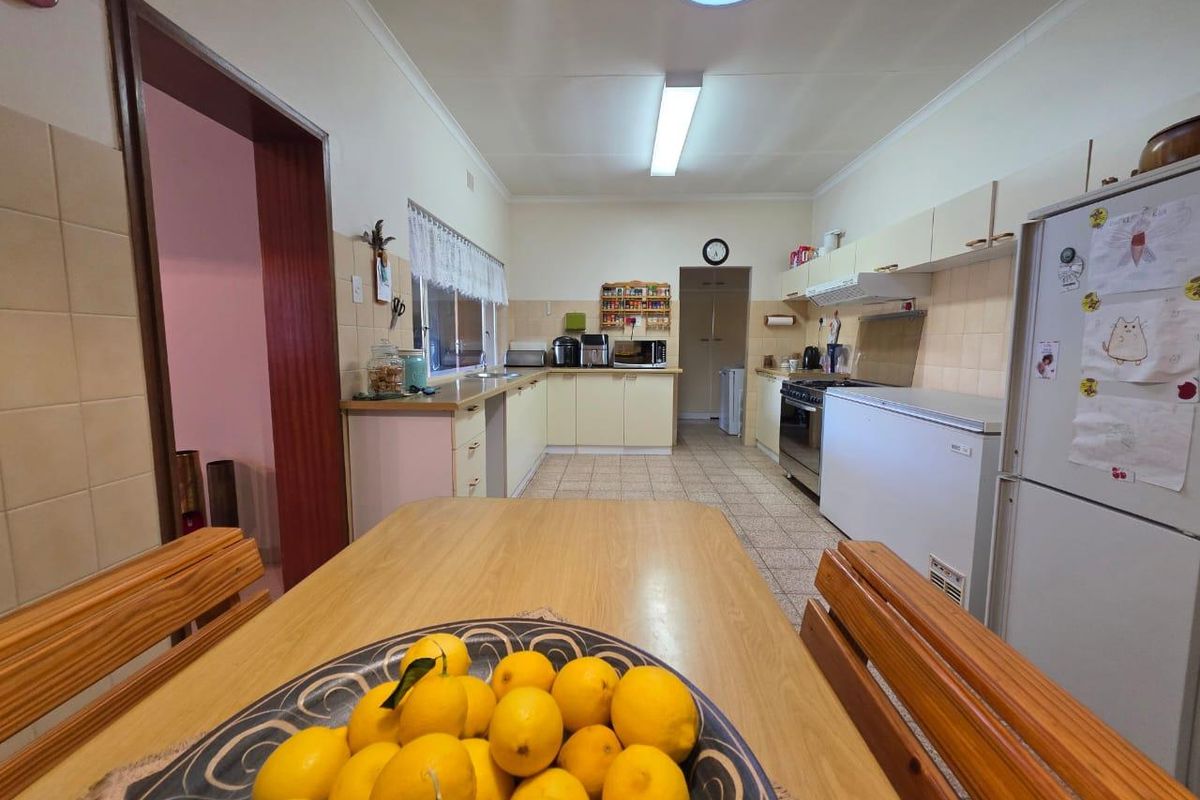 A functional kitchen featuring tiled flooring, built-in cabinetry, a tiled backsplash, and a freestanding oven with an extractor fan.