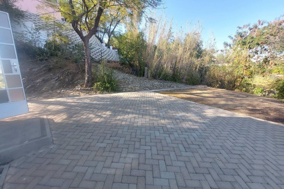 A paved rear patio area featuring a retaining wall and established garden landscaping.