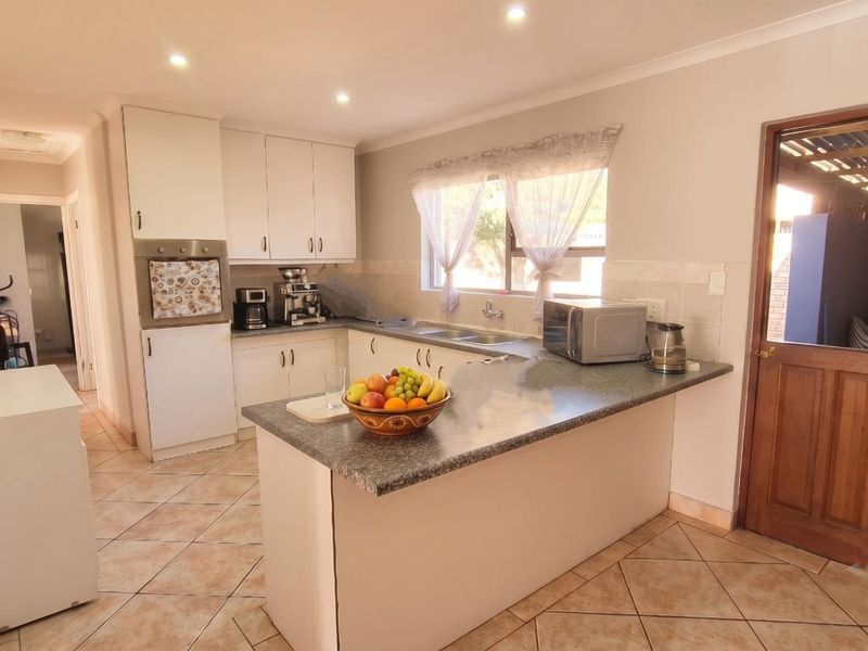 Functional kitchen featuring white cabinetry, laminate countertops, a double basin sink, built-in oven, and tiled flooring with a classic stable door entrance.