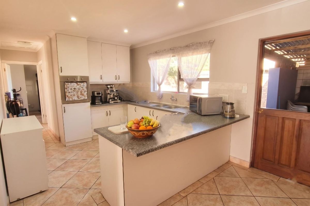Functional kitchen featuring white cabinetry, laminate countertops, a double basin sink, built-in oven, and tiled flooring with a classic stable door entrance.