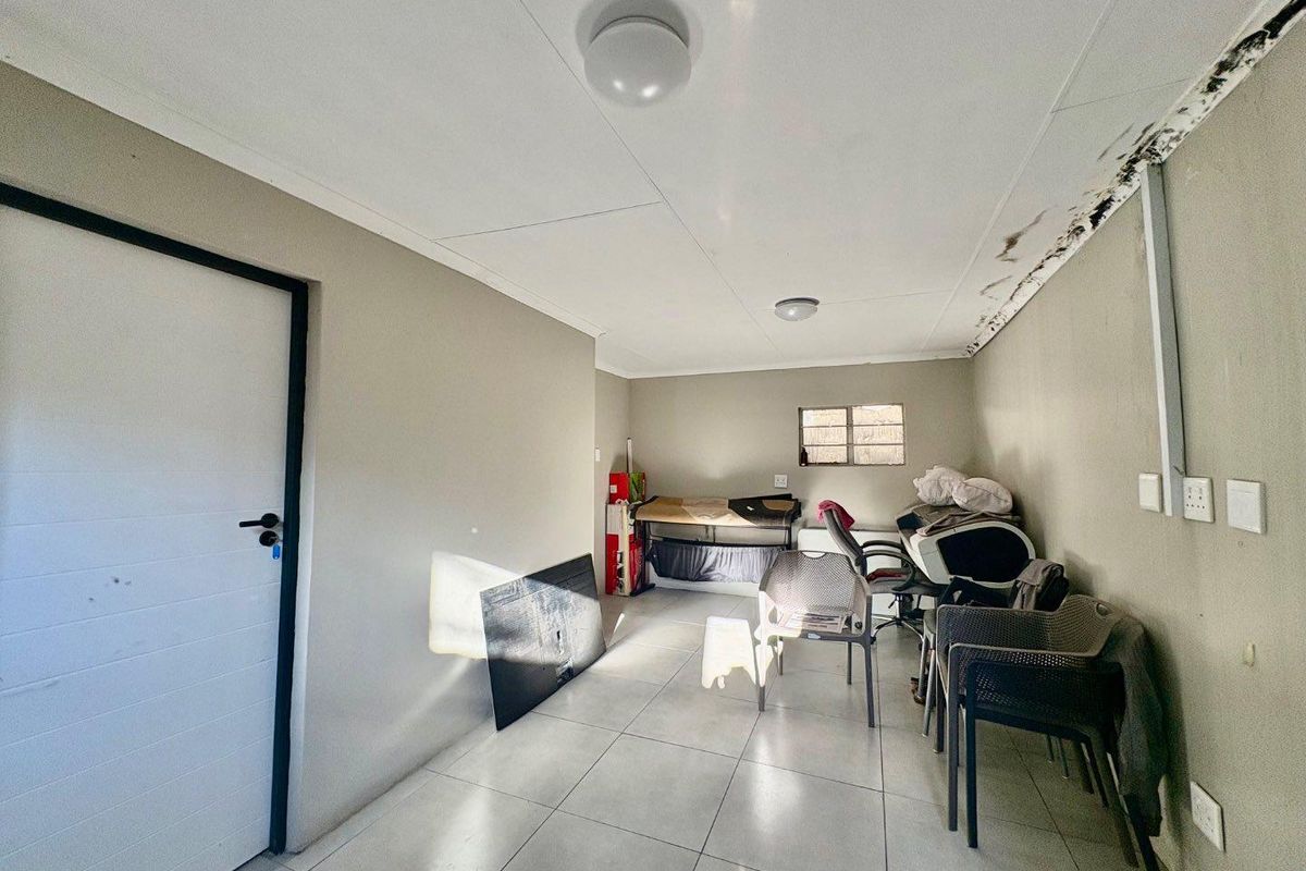 A bedroom space featuring tiled flooring and ceiling lighting, currently showing signs of water damage along the wall and ceiling junction.