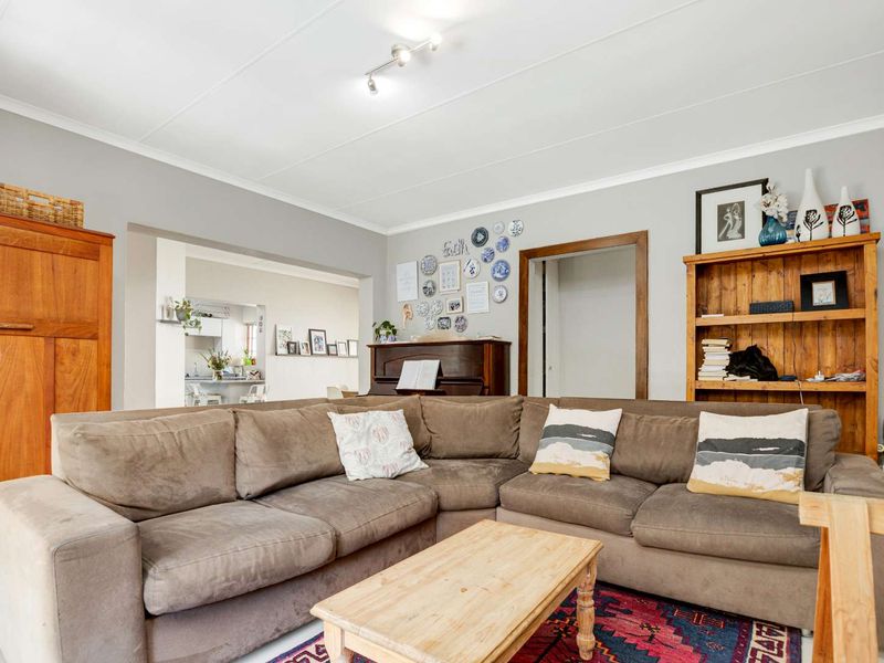 A comfortable living room featuring tiled flooring, neutral wall tones, and an open archway leading to the adjacent kitchen area.