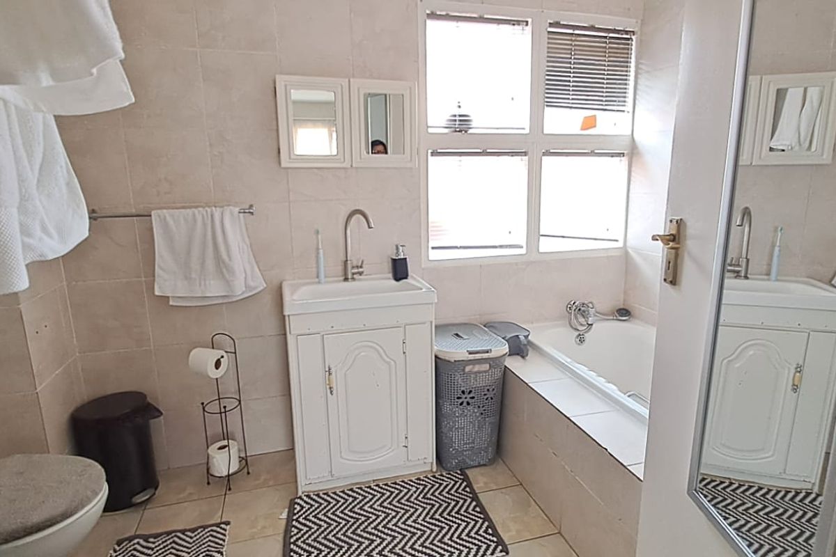 A functional bathroom featuring a built-in bathtub, a vanity cabinet with a basin, and a separate shower enclosure with tiled finishes throughout.