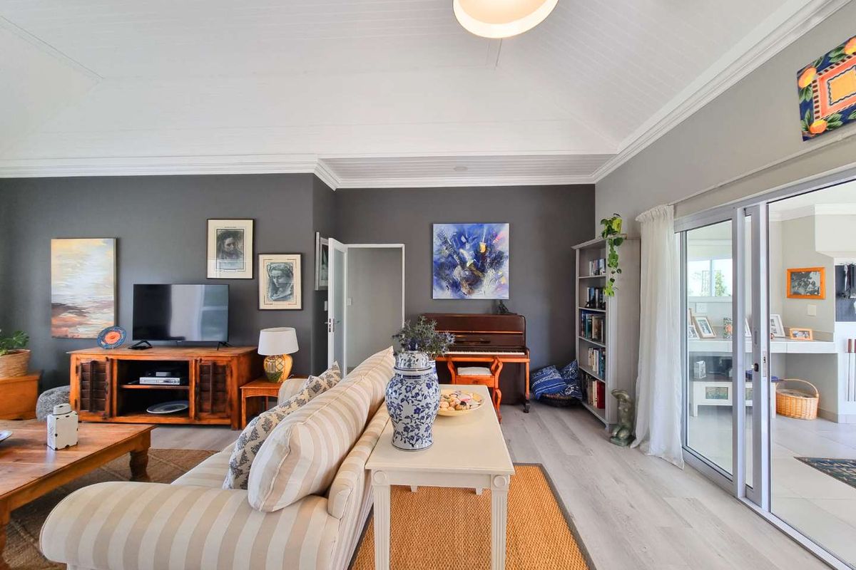 A spacious living room featuring high vaulted ceilings, modern laminate flooring, and large sliding glass doors that provide seamless access to the outdoor patio area.