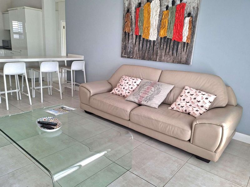 An open-plan living area featuring tiled flooring, a breakfast bar, and a modern kitchen with white cabinetry.