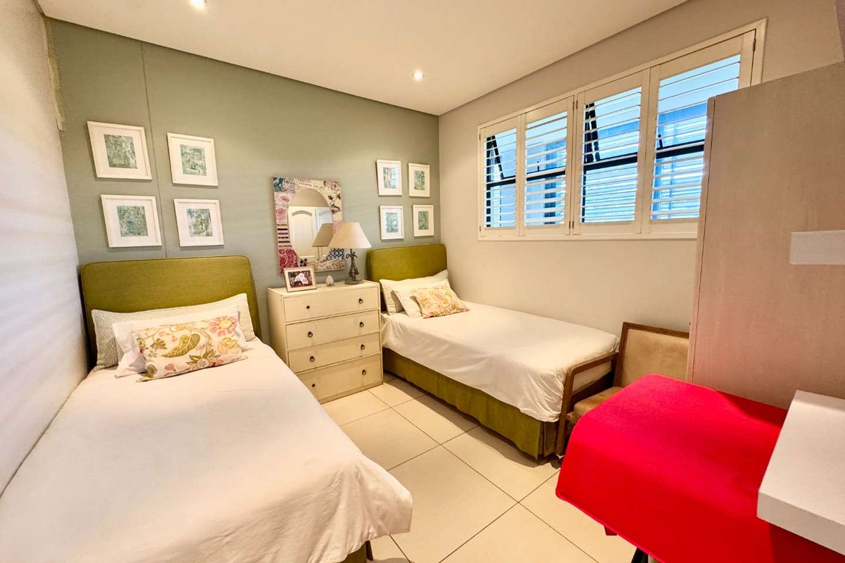 A well-maintained bedroom featuring tiled flooring, recessed ceiling lighting, and white plantation shutters on the windows.