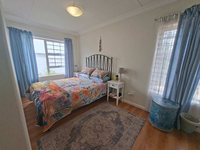 A well-lit bedroom featuring laminate flooring, coved ceilings, and dual windows that provide natural light.
