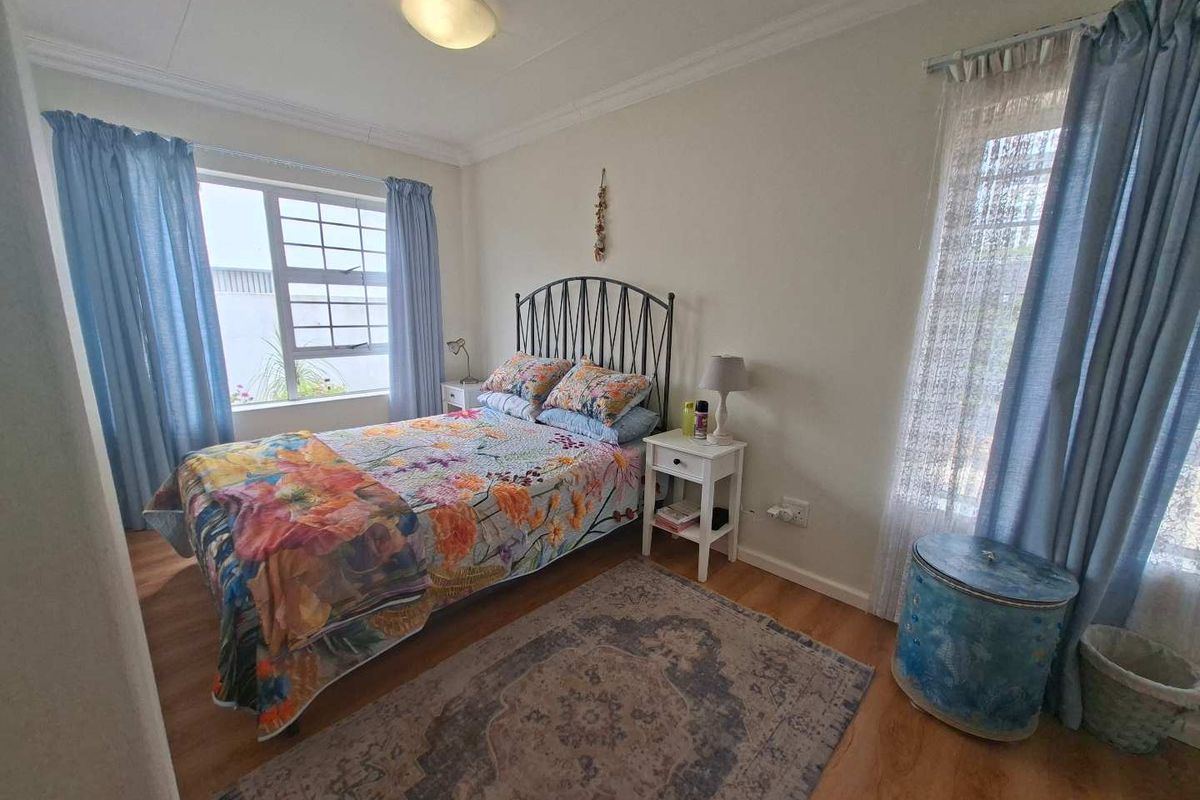 A well-lit bedroom featuring laminate flooring, coved ceilings, and dual windows that provide natural light.