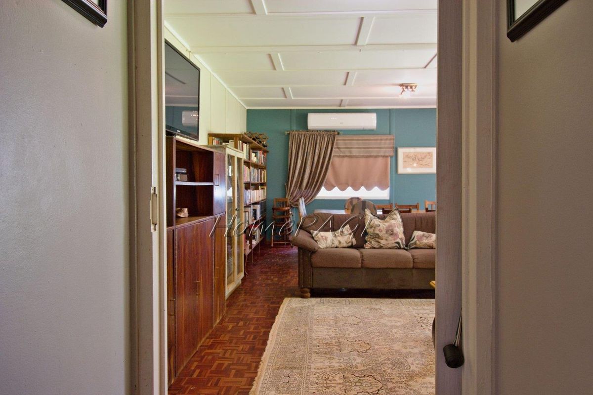 A view into a living area featuring parquet flooring, a coffered ceiling, and a wall-mounted air conditioning unit.