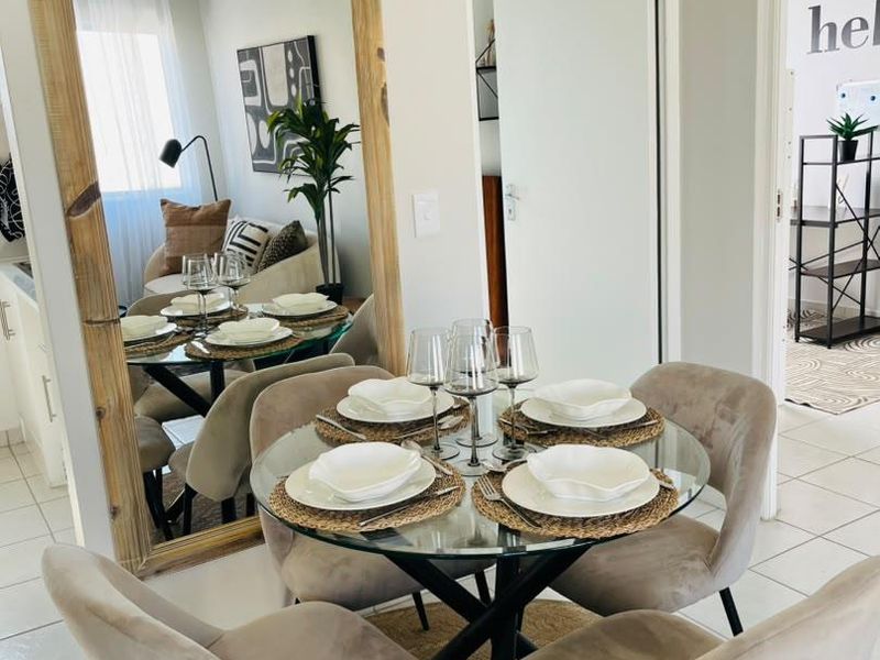 A bright dining area featuring neutral tiled flooring and a clear view into the adjacent living space.