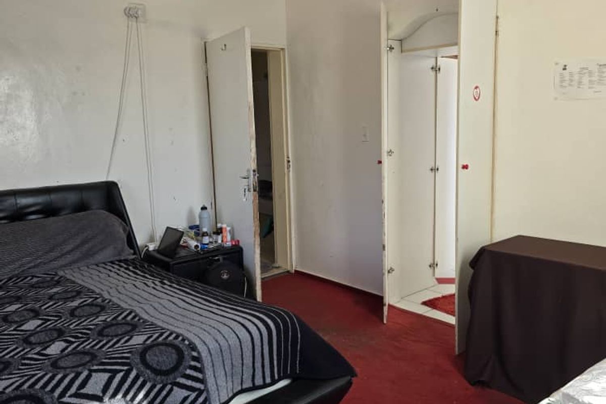 A bedroom featuring red carpeting, built-in closet space, and direct access to an adjoining room.