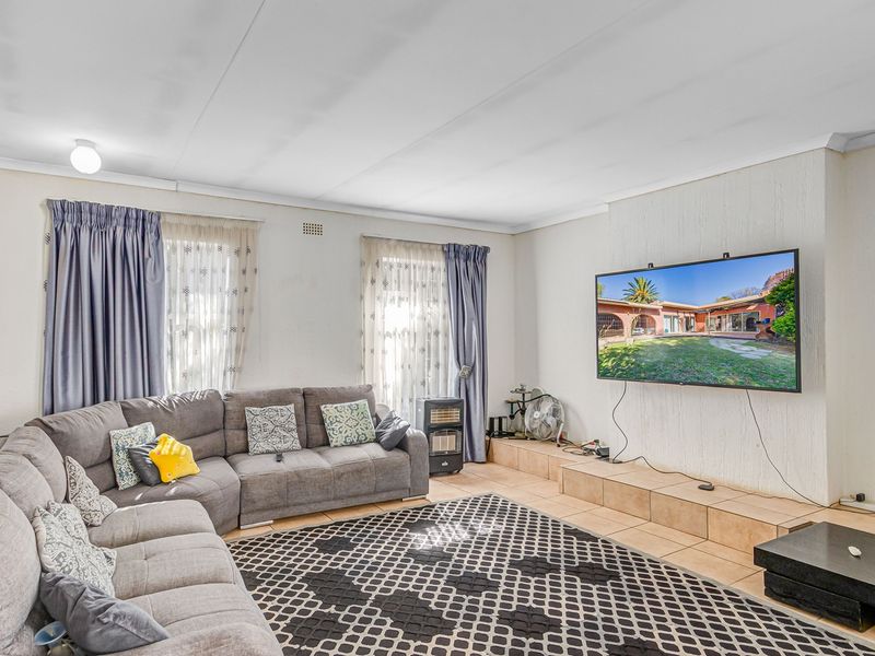 Spacious living room featuring a raised tiled platform, textured wall finishes, and coved ceilings, providing a comfortable and functional family area.