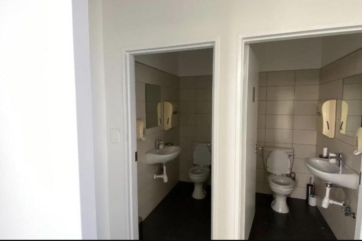 Two functional commercial bathrooms featuring wall-mounted washbasins, toilets, and tiled finishes.
