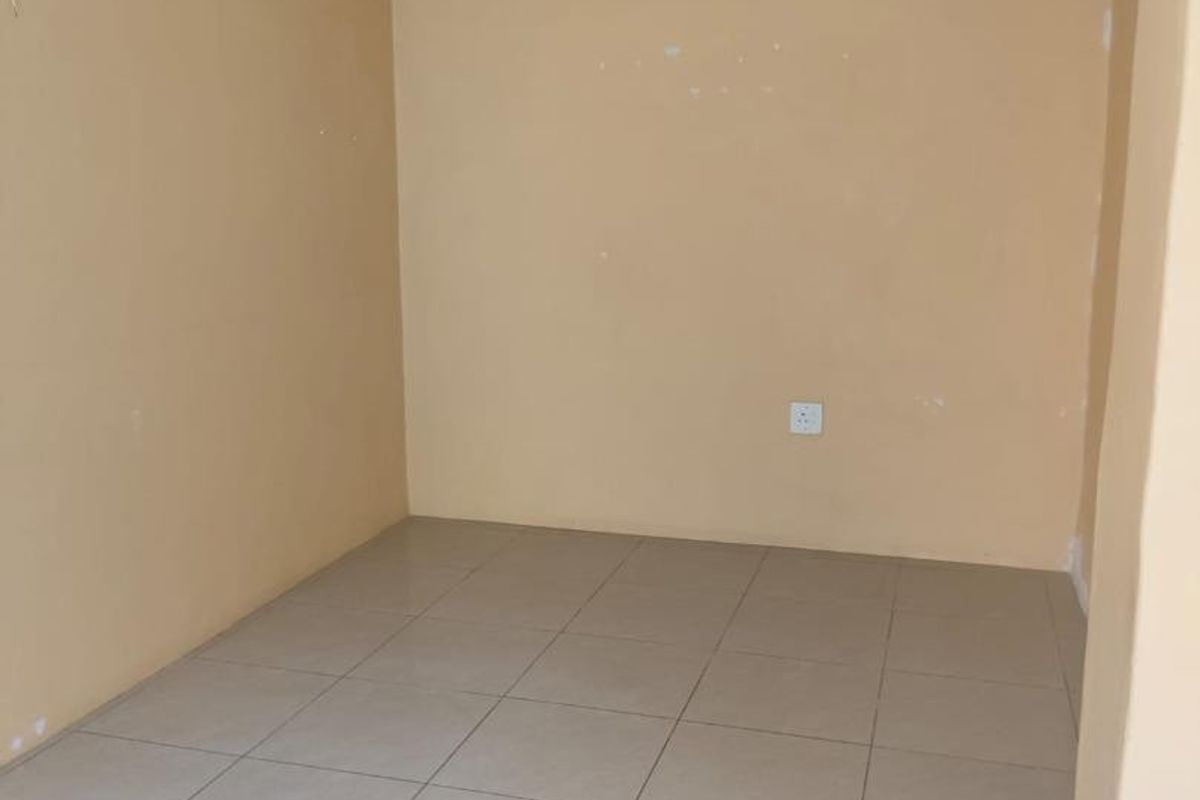 An empty bedroom featuring neutral tiled flooring and a central ceiling light fixture, ready for personalization.