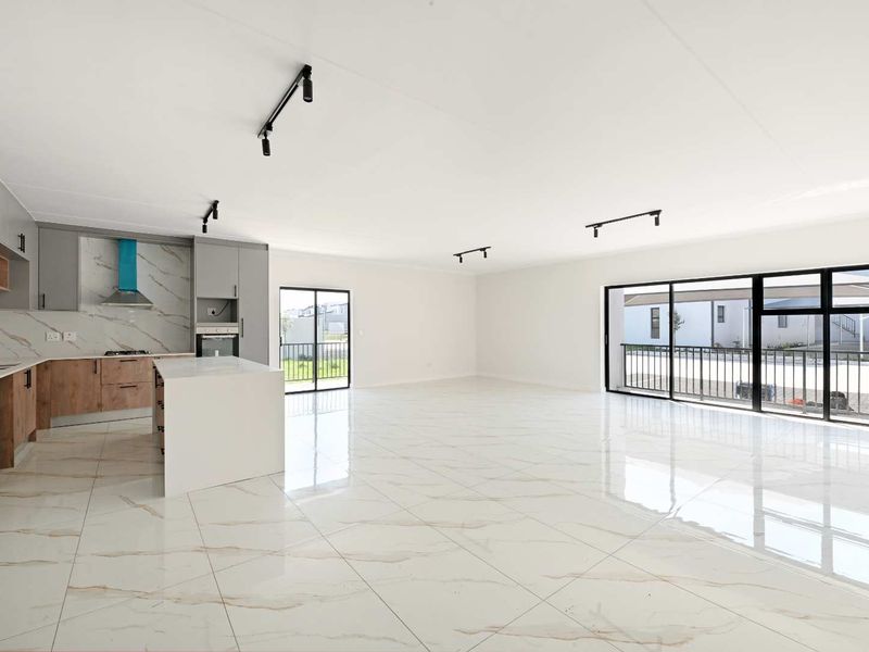 Spacious open-plan living area featuring a modern kitchen with stone countertops, built-in appliances, and polished marble-look floor tiles throughout.
