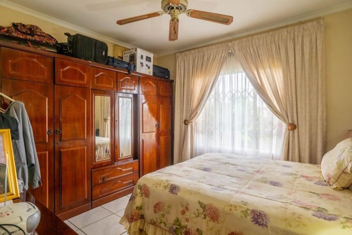 A bedroom featuring built-in wooden cupboards, tiled flooring, and a ceiling fan, offering a functional and traditional layout.