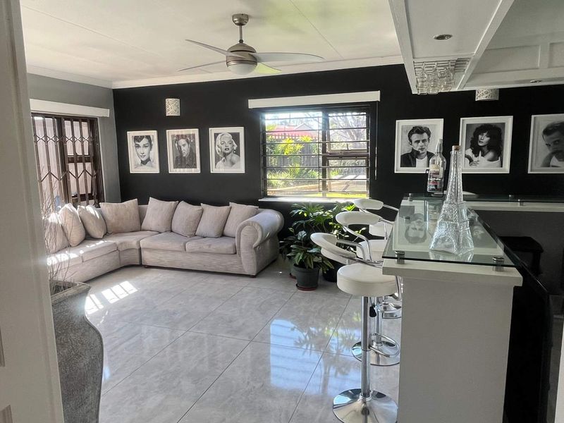 Spacious living area featuring a built-in bar, modern tiled flooring, and a ceiling fan, creating a stylish and functional entertainment space.