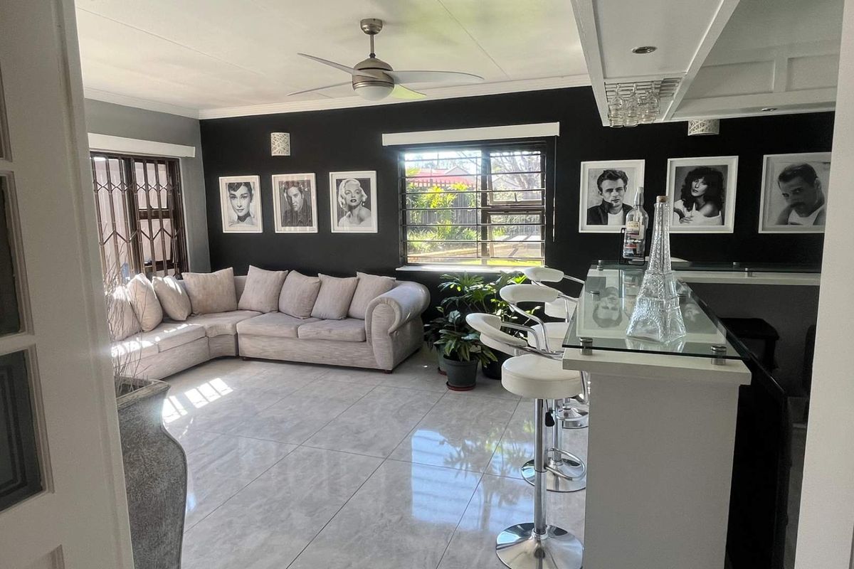 Spacious living area featuring a built-in bar, modern tiled flooring, and a ceiling fan, creating a stylish and functional entertainment space.