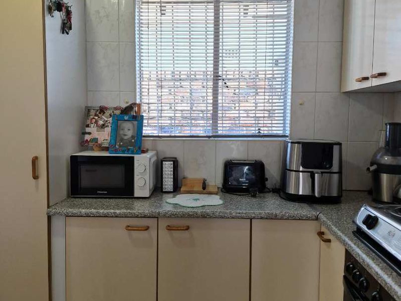 A functional kitchen featuring laminate cabinetry, tiled splashbacks, and built-in cooking appliances, offering a practical layout for daily meal preparation.