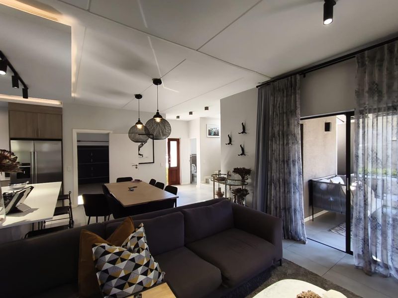Spacious open-plan living and dining area featuring modern recessed lighting, sleek kitchen cabinetry, and large sliding doors leading to an outdoor patio space.