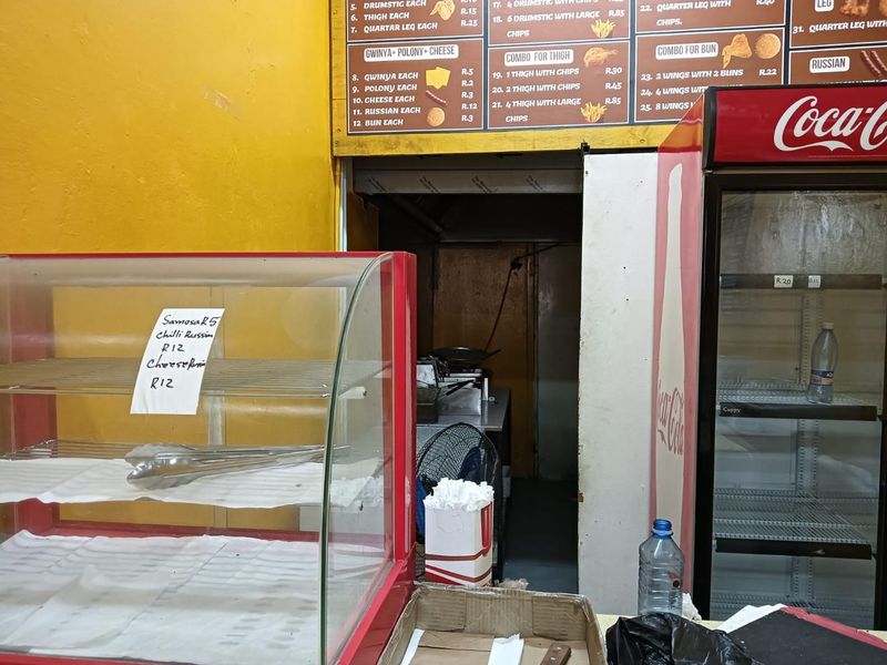 A commercial kitchen service area featuring a menu board, display counter, and integrated refrigeration unit for food service operations.