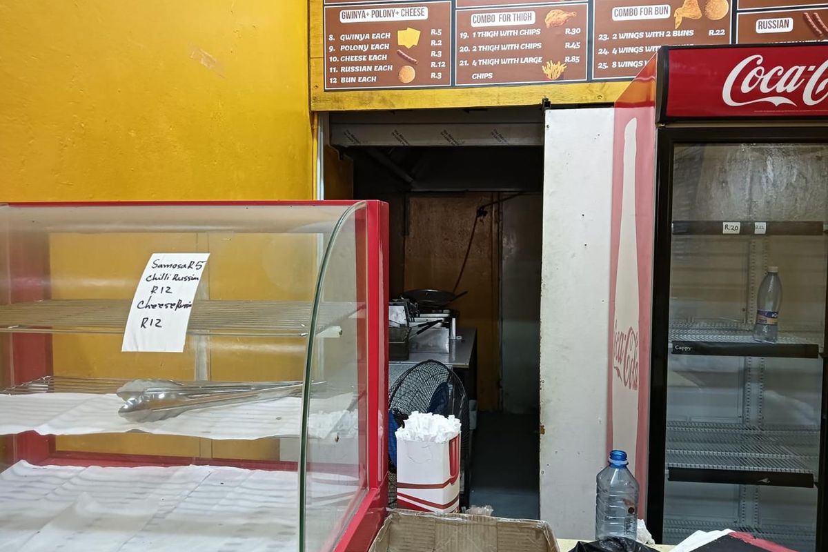 A commercial kitchen service area featuring a menu board, display counter, and integrated refrigeration unit for food service operations.