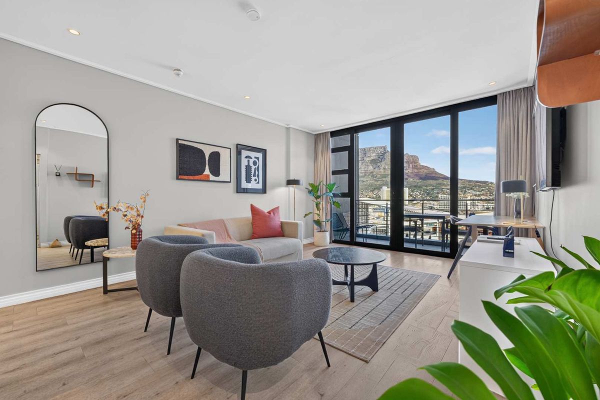 Modern living room featuring light laminate flooring, recessed lighting, and large sliding glass doors opening to a balcony with mountain views.