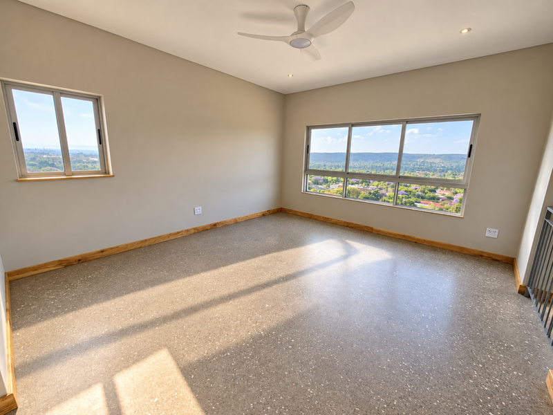 A bright, empty bedroom featuring modern terrazzo flooring, a ceiling fan, and expansive windows offering panoramic views of the surrounding landscape.