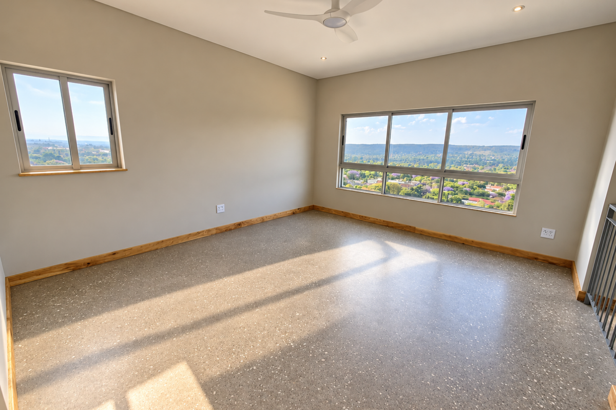 A bright, empty bedroom featuring modern terrazzo flooring, a ceiling fan, and expansive windows offering panoramic views of the surrounding landscape.