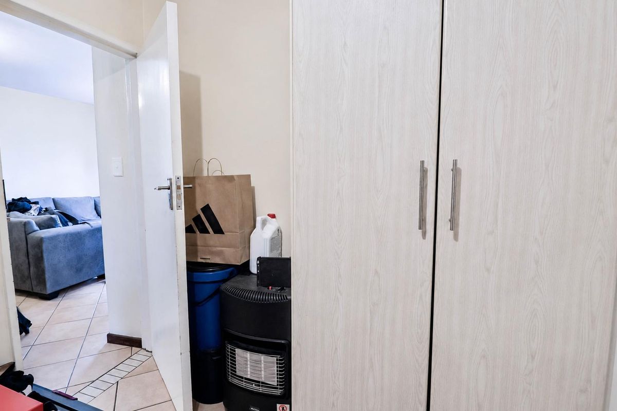 A view of a bedroom featuring built-in light wood-grain cabinetry and tiled flooring, with a doorway leading into an adjacent living area.