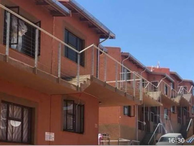 Exterior view of a multi-story apartment complex featuring balconies, external staircases, and security bars on windows.