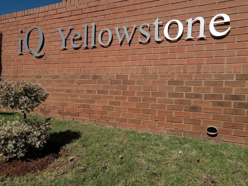A clear view of the brick boundary wall featuring the iQ Yellowstone complex signage.