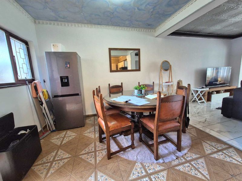 Open plan living and dining area featuring decorative ceiling details and tiled flooring throughout.