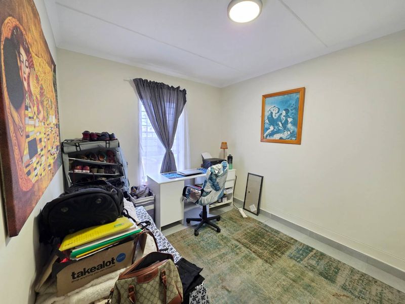 A functional bedroom featuring tiled flooring, a central ceiling light, and a window with a curtain rail, suitable for use as a bedroom or office.