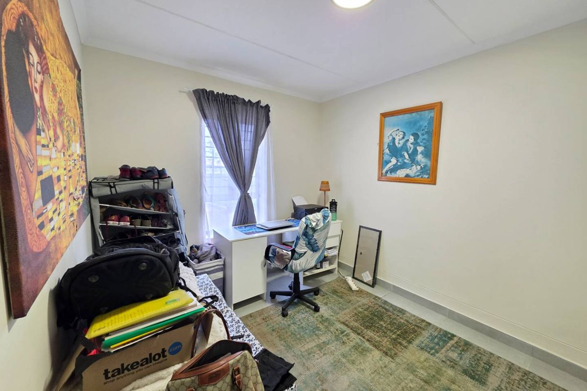 A functional bedroom featuring tiled flooring, a central ceiling light, and a window with a curtain rail, suitable for use as a bedroom or office.