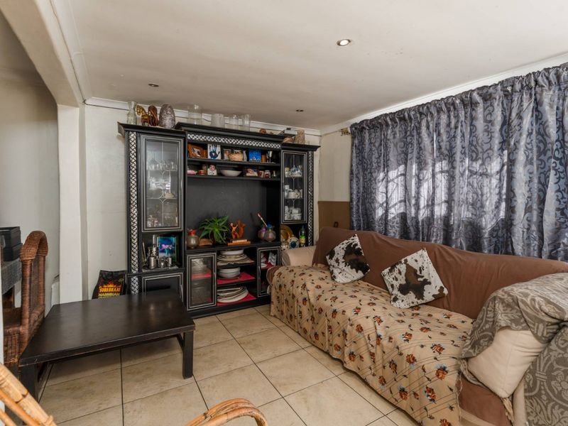 A living room featuring tiled flooring and recessed downlights, offering a functional space ready for cosmetic updates.