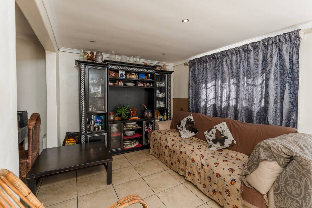 A living room featuring tiled flooring and recessed downlights, offering a functional space ready for cosmetic updates.