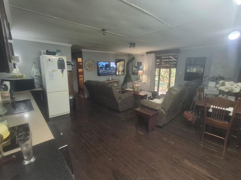 Open-plan living and kitchen area featuring dark hardwood flooring, a fireplace, and direct access to an outdoor patio space.