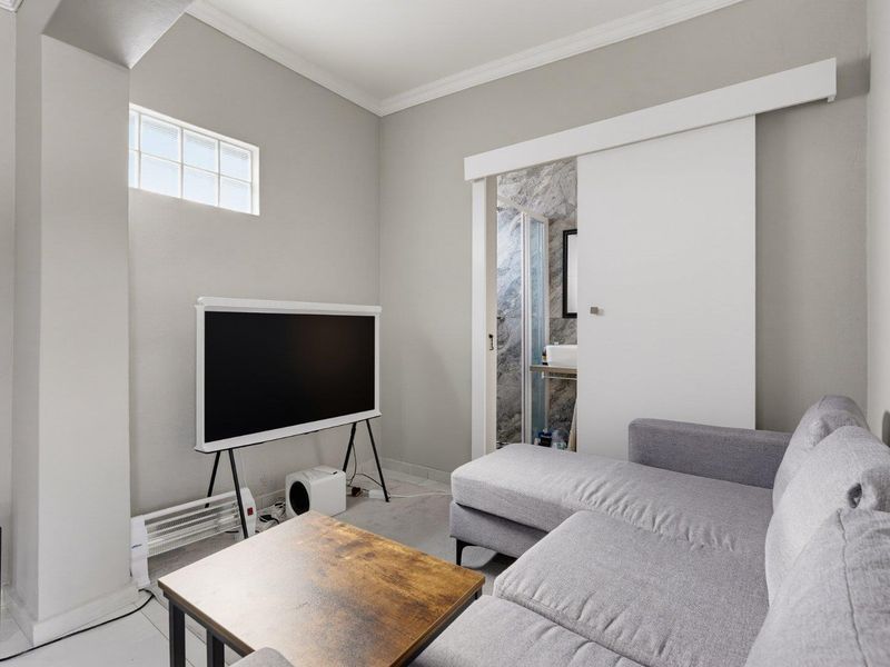 A well-maintained living area featuring neutral walls, coving, and a sliding door providing direct access to an adjoining bathroom.
