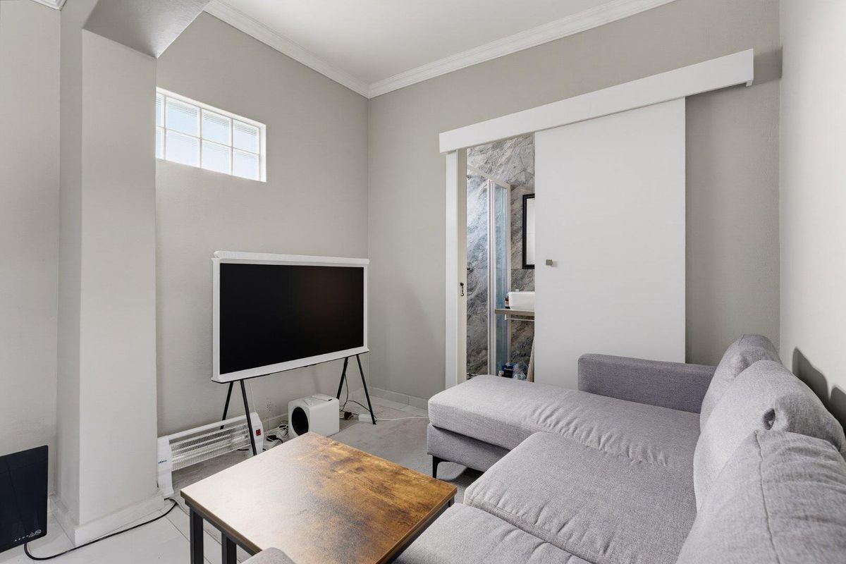 A well-maintained living area featuring neutral walls, coving, and a sliding door providing direct access to an adjoining bathroom.