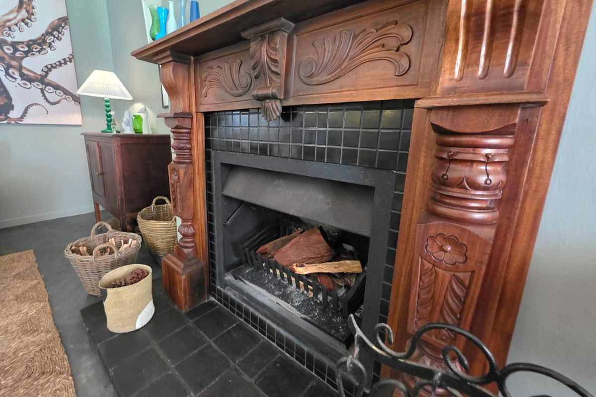 A classic living room featuring an ornate, carved wooden fireplace mantel with a black tiled hearth and surround.