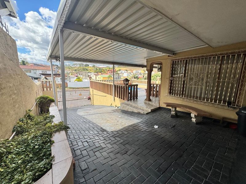 Covered outdoor patio area featuring paved flooring, security features, and a metal roof structure, providing a functional space for outdoor living.