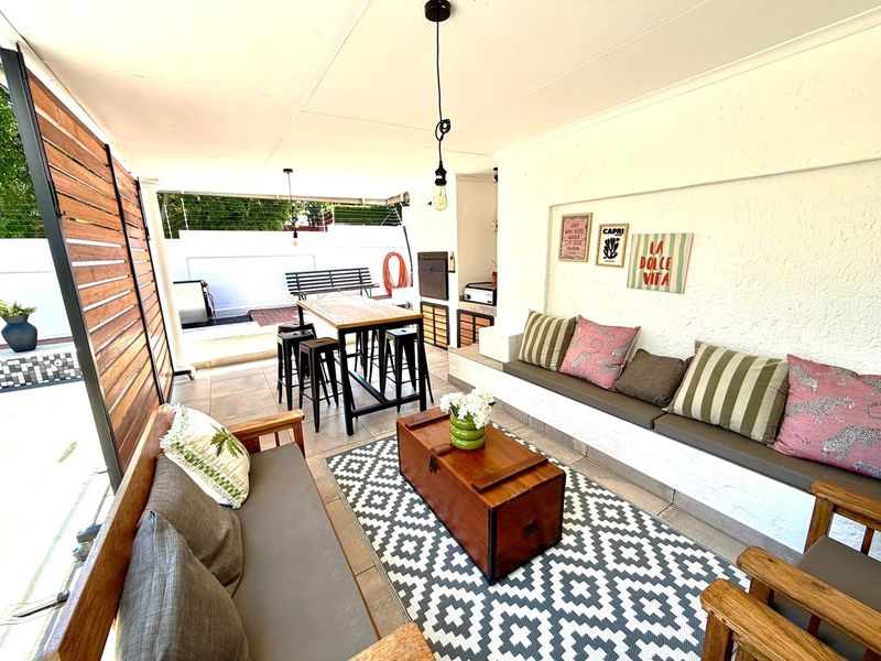 Covered outdoor patio featuring built-in bench seating, a built-in braai, and tiled flooring, ideal for relaxed outdoor entertaining.